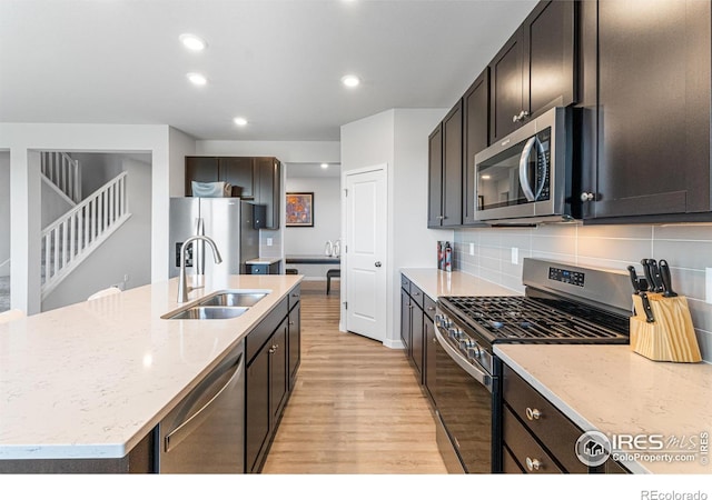 5766 Ranch St, Longmont, CO 80504 - kitchen featuring stainless steel appliances, light wood-style flooring, decorative backsplash, light stone countertops, and recessed lighting