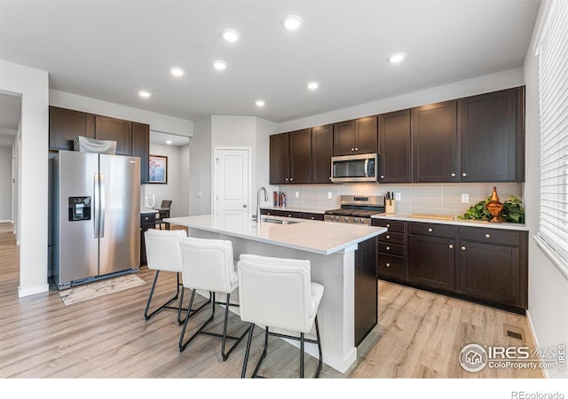 5766 Ranch St, Longmont, CO 80504 - kitchen featuring stainless steel appliances, light wood-type flooring, dark brown cabinetry, decorative backsplash, and recessed lighting