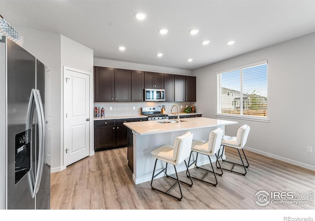 5766 Ranch St, Longmont, CO 80504 - kitchen with stainless steel appliances, light wood finished floors, a kitchen breakfast bar, dark brown cabinets, and light countertops