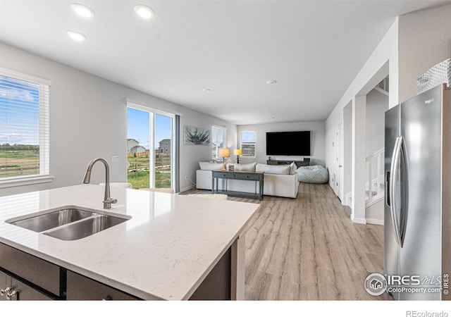 5766 Ranch St, Longmont, CO 80504 - kitchen with stainless steel fridge with ice dispenser, light wood-style floors, recessed lighting, light stone countertops, and plenty of natural light