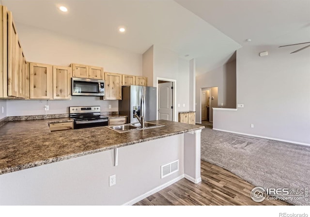 1541 Water Vista Ln, Severance, CO 80550 - kitchen featuring stainless steel appliances, light brown cabinets, dark countertops, a peninsula, and high vaulted ceiling