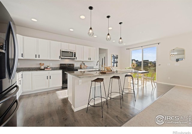 5217 Alberta Falls St, Timnath, CO 80547 - kitchen with stainless steel appliances, recessed lighting, wood finished floors, a breakfast bar area, and white cabinetry
