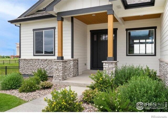 24113 E 36th Pl, Aurora, CO 80019 - view of exterior entry featuring stone siding, board and batten siding, and covered porch