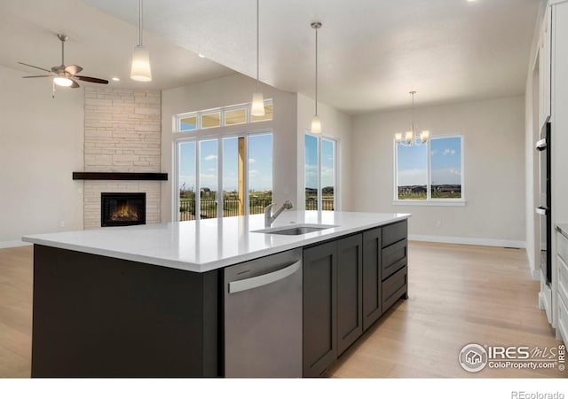 24113 E 36th Pl, Aurora, CO 80019 - kitchen with stainless steel appliances, light wood-style flooring, a ceiling fan, and a stone fireplace