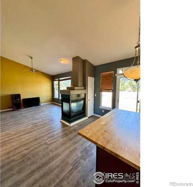 2395 Sandpiper Dr, Lafayette, CO 80026 - kitchen featuring lofted ceiling, a tile fireplace, dark wood finished floors, a ceiling fan, and pendant lighting