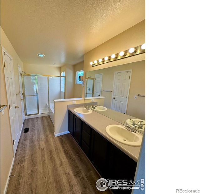 2395 Sandpiper Dr, Lafayette, CO 80026 - bathroom featuring a shower stall, wood finished floors, double vanity, and a textured ceiling