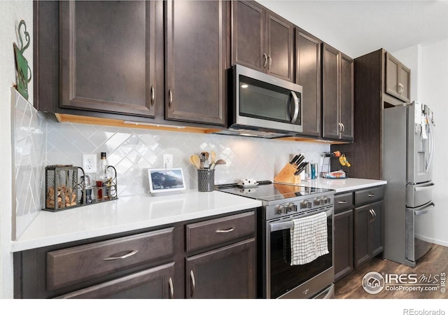 14203 Hop Clover Trl, Parker, CO 80134 - kitchen with appliances with stainless steel finishes, dark brown cabinets, dark wood-style floors, light countertops, and tasteful backsplash