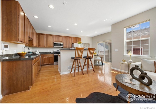 3882 W 118th Pl, Westminster, CO 80031 - kitchen featuring stainless steel appliances, a breakfast bar area, light wood-style floors, dark countertops, and recessed lighting