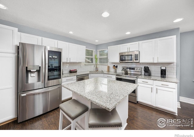 2302 74th Ave, Greeley, CO 80634 - kitchen featuring appliances with stainless steel finishes, decorative backsplash, white cabinets, a center island, and recessed lighting
