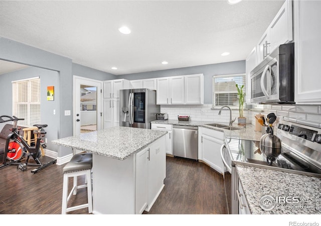 2302 74th Ave, Greeley, CO 80634 - kitchen with stainless steel appliances, dark wood-style flooring, a center island, decorative backsplash, and white cabinets