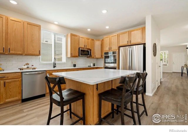 2262 Harvest St, Fort Collins, CO 80528 - kitchen with stainless steel appliances, a breakfast bar area, light wood finished floors, tasteful backsplash, and recessed lighting