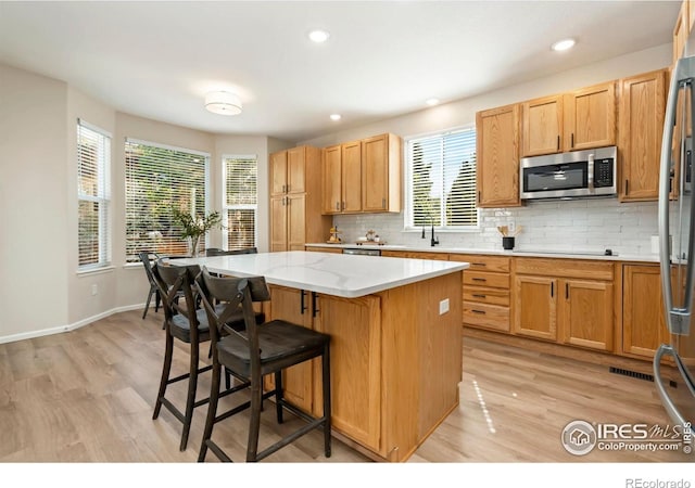 2262 Harvest St, Fort Collins, CO 80528 - kitchen featuring stainless steel appliances, light wood-type flooring, a kitchen island, decorative backsplash, and recessed lighting