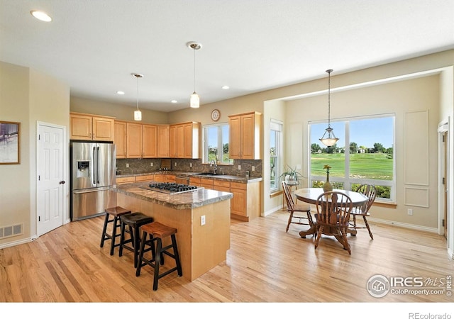 1145 Wyndemere Cir, Longmont, CO 80504 - kitchen with stainless steel appliances, a kitchen island, backsplash, light wood-style flooring, and recessed lighting