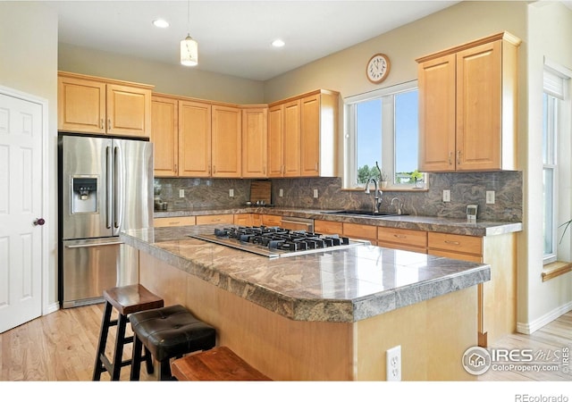 1145 Wyndemere Cir, Longmont, CO 80504 - kitchen featuring stainless steel appliances, tile counters, a kitchen island, light brown cabinetry, and a kitchen breakfast bar