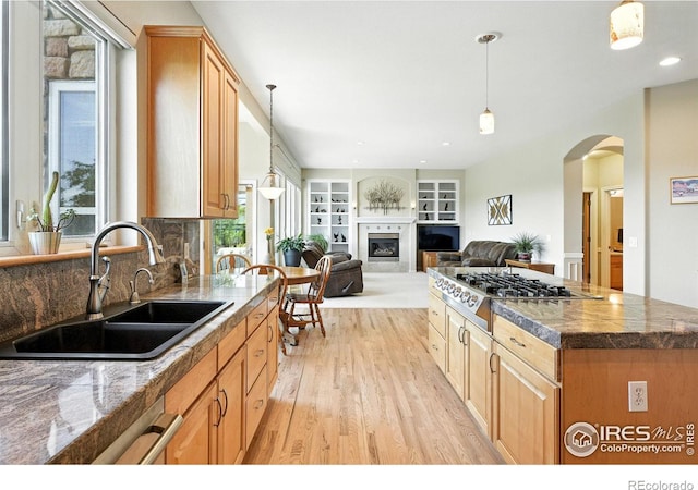 1145 Wyndemere Cir, Longmont, CO 80504 - kitchen featuring stainless steel gas cooktop, light wood-style floors, arched walkways, hanging light fixtures, and recessed lighting