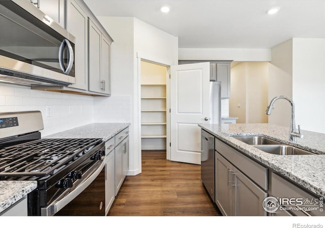 9929 Ceylon Ct, Commerce City, CO 80022 - kitchen featuring stainless steel appliances, gray cabinets, dark wood finished floors, recessed lighting, and decorative backsplash