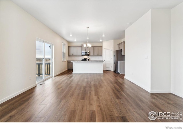 9929 Ceylon Ct, Commerce City, CO 80022 - kitchen with appliances with stainless steel finishes, a chandelier, gray cabinetry, open floor plan, and dark wood-style flooring