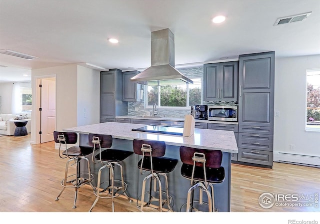 11230 W 77th Dr, Arvada, CO 80005 - kitchen with island range hood, stainless steel microwave, gray cabinets, a kitchen bar, and backsplash