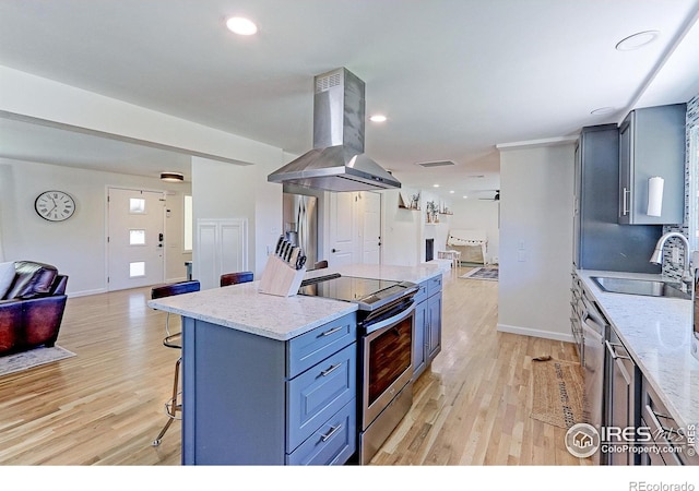 11230 W 77th Dr, Arvada, CO 80005 - kitchen featuring open floor plan, island range hood, appliances with stainless steel finishes, light wood-type flooring, and recessed lighting