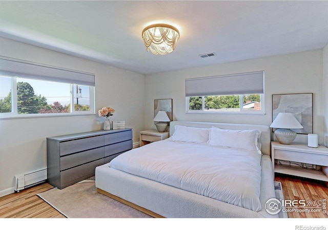 11230 W 77th Dr, Arvada, CO 80005 - bedroom with a baseboard radiator, wood finished floors, and a chandelier
