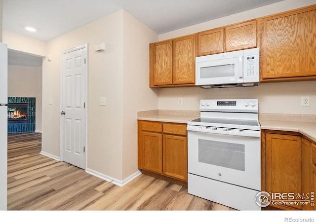 2702 Rigden Pkwy Unit F4, Fort Collins, CO 80525 - kitchen with white appliances, light wood finished floors, light countertops, and brown cabinetry
