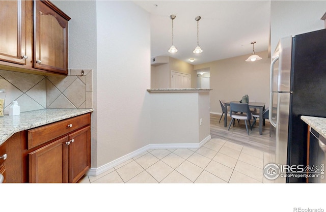 2133 Krisron Rd Unit D103, Fort Collins, CO 80525 - kitchen featuring freestanding refrigerator, decorative backsplash, decorative light fixtures, brown cabinetry, and light stone counters