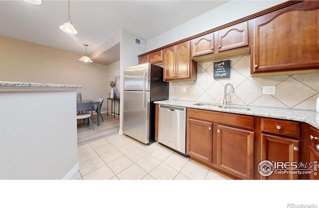 2133 Krisron Rd Unit D103, Fort Collins, CO 80525 - kitchen featuring appliances with stainless steel finishes, backsplash, hanging light fixtures, light stone countertops, and brown cabinetry