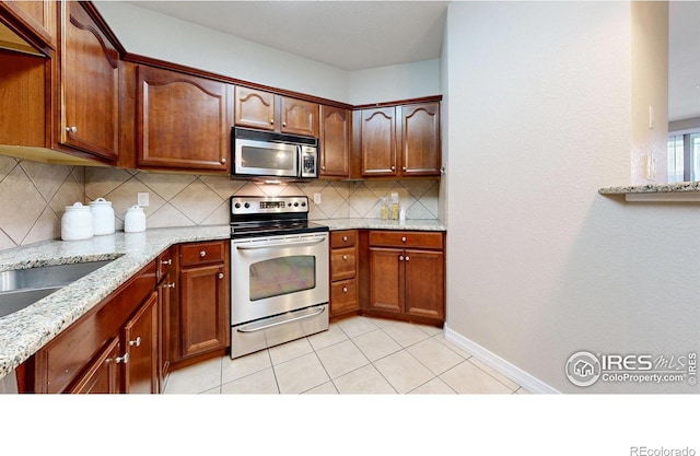 2133 Krisron Rd Unit D103, Fort Collins, CO 80525 - kitchen with appliances with stainless steel finishes, tasteful backsplash, light stone countertops, and light tile patterned flooring