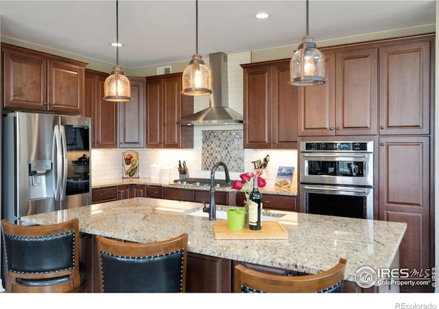 3304 Heron Lakes Pkwy, Berthoud, CO 80513 - kitchen with stainless steel appliances, wall chimney exhaust hood, light stone counters, tasteful backsplash, and a kitchen bar