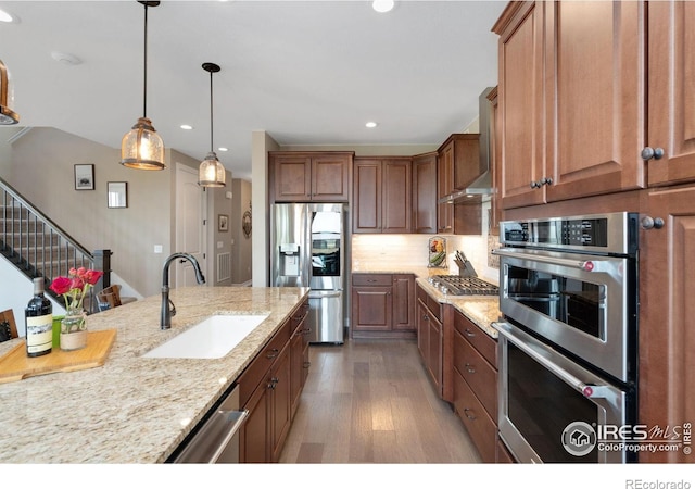 3304 Heron Lakes Pkwy, Berthoud, CO 80513 - kitchen with appliances with stainless steel finishes, wood finished floors, recessed lighting, wall chimney exhaust hood, and light stone counters