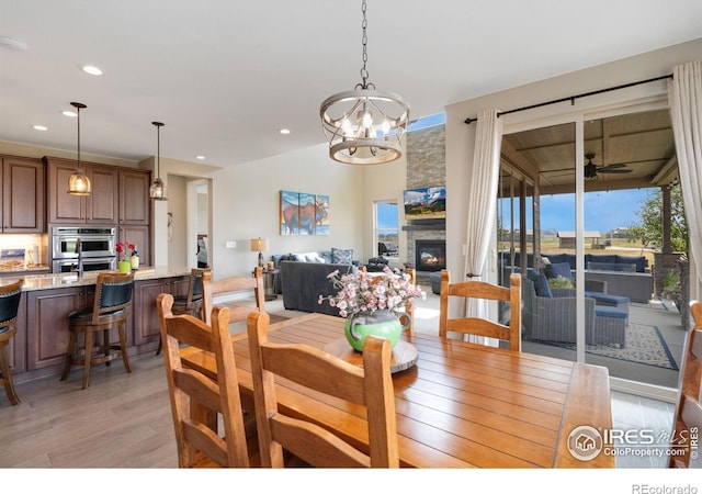 3304 Heron Lakes Pkwy, Berthoud, CO 80513 - dining room with light wood-style flooring, a fireplace, a chandelier, recessed lighting, and ceiling fan