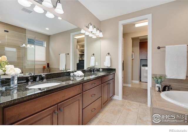 3304 Heron Lakes Pkwy, Berthoud, CO 80513 - full bathroom with double vanity, tile patterned floors, a garden tub, a stall shower, and washer / clothes dryer