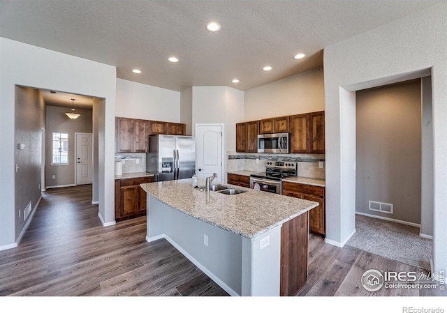604 Rosedale St, Severance, CO 80550 - kitchen with appliances with stainless steel finishes, decorative backsplash, dark wood finished floors, a center island with sink, and recessed lighting