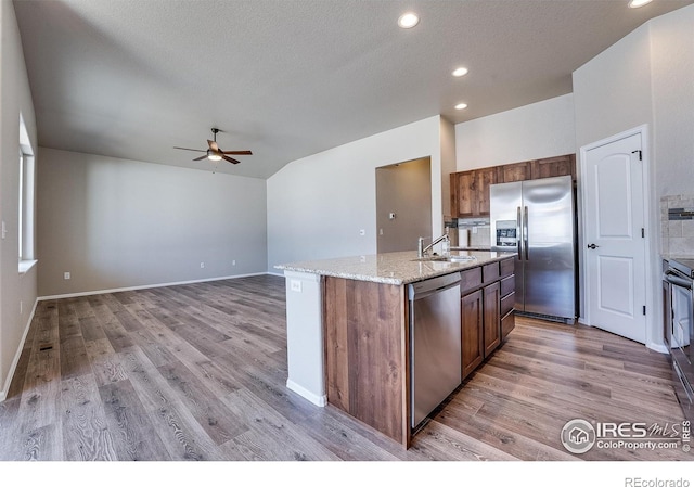 604 Rosedale St, Severance, CO 80550 - kitchen featuring appliances with stainless steel finishes, ceiling fan, light wood-type flooring, a kitchen island with sink, and light stone counters