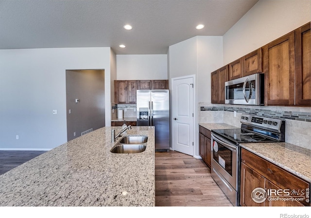 604 Rosedale St, Severance, CO 80550 - kitchen featuring stainless steel appliances, wood finished floors, tasteful backsplash, light stone counters, and recessed lighting