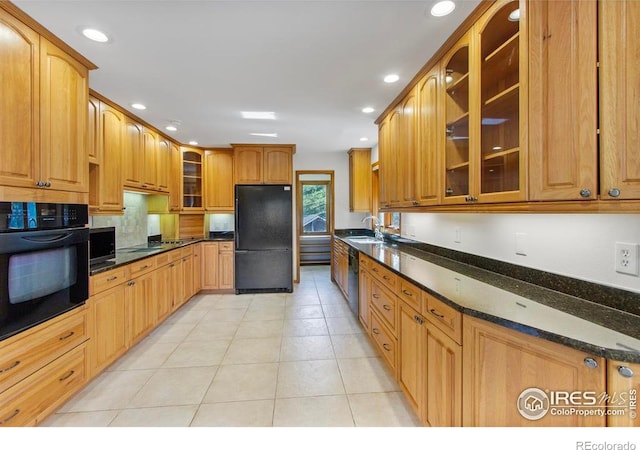 2160 Devils Gulch Rd, Estes Park, CO 80517 - kitchen with black appliances, light tile patterned floors, recessed lighting, dark stone counters, and glass insert cabinets