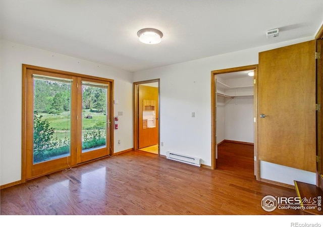 2160 Devils Gulch Rd, Estes Park, CO 80517 - unfurnished bedroom featuring a baseboard radiator, wood finished floors, access to outside, and a spacious closet