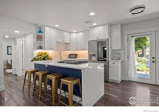 7131 Pontiac St, Commerce City, CO 80022 - kitchen featuring stainless steel appliances, open shelves, white cabinetry, a breakfast bar area, and decorative backsplash