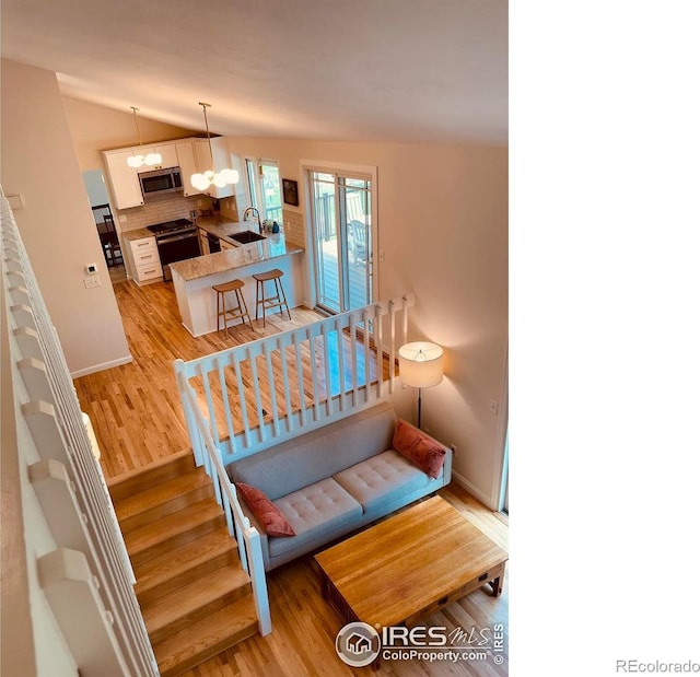 4303 30th St, Boulder, CO 80301 - staircase featuring wood finished floors, vaulted ceiling, and a chandelier