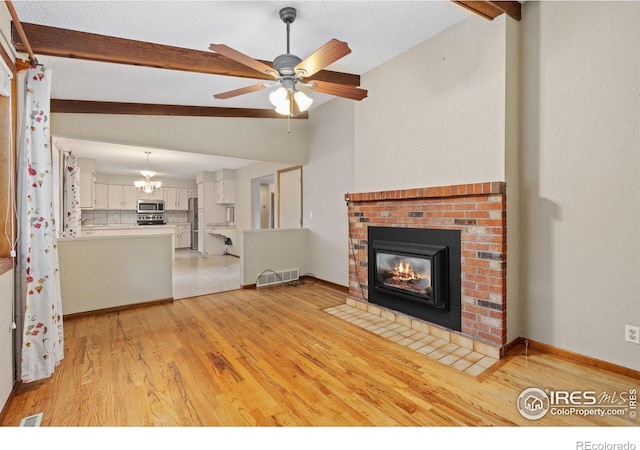 2516 Mountain View Ave, Longmont, CO 80503 - unfurnished living room featuring a brick fireplace, light wood-type flooring, ceiling fan, and a chandelier