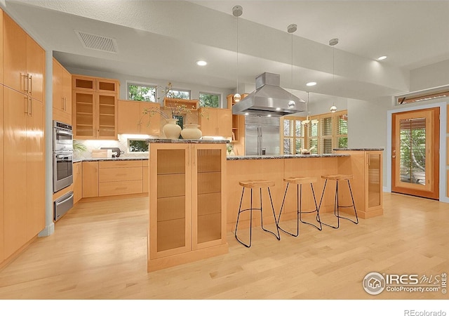 2861 Shoshone Trl, Lafayette, CO 80026 - kitchen featuring island exhaust hood, appliances with stainless steel finishes, a warming drawer, light wood-style flooring, and light brown cabinetry
