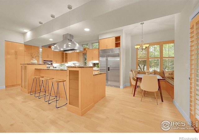 2861 Shoshone Trl, Lafayette, CO 80026 - kitchen with island exhaust hood, stainless steel appliances, open shelves, light wood finished floors, and a breakfast bar area