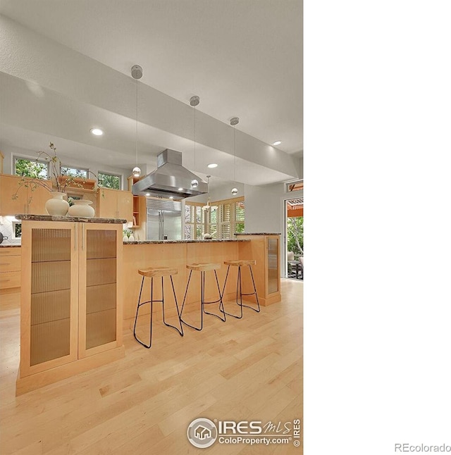 2861 Shoshone Trl, Lafayette, CO 80026 - kitchen with island range hood, light wood-type flooring, a breakfast bar, decorative light fixtures, and stone countertops