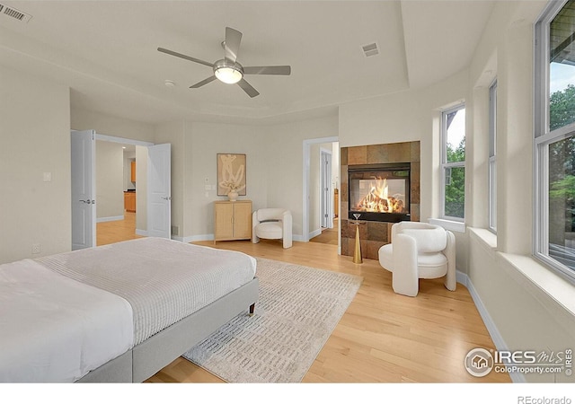 2861 Shoshone Trl, Lafayette, CO 80026 - bedroom featuring light wood-style flooring, a tile fireplace, and a ceiling fan