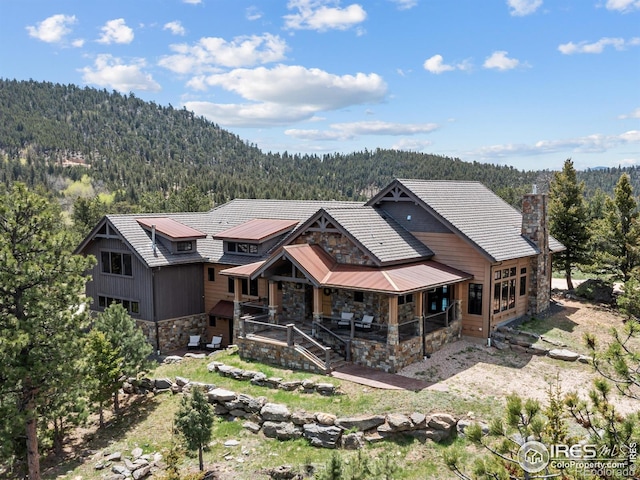 3411 Hillcrest Ln, Estes Park, CO 80517 - back of property featuring stone siding, a wooded view, and a porch