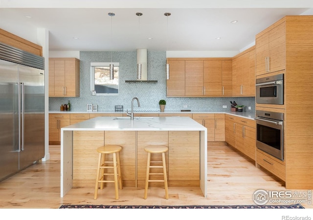 514 Granite Dr, Boulder, CO 80302 - kitchen with built in fridge, wall chimney exhaust hood, light wood-style flooring, an island with sink, and decorative backsplash