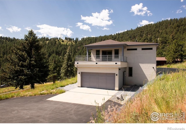 514 Granite Dr, Boulder, CO 80302 - modern home with a balcony, a wooded view, concrete driveway, stucco siding, and a garage