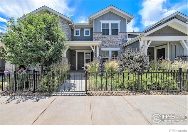 2470 Trio Falls Dr, Loveland, CO 80538 - view of front of property with stone siding, board and batten siding, a fenced front yard, and a gate