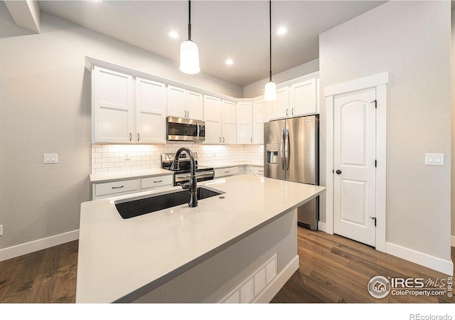 2470 Trio Falls Dr, Loveland, CO 80538 - kitchen featuring appliances with stainless steel finishes, tasteful backsplash, white cabinetry, dark wood-style flooring, and recessed lighting