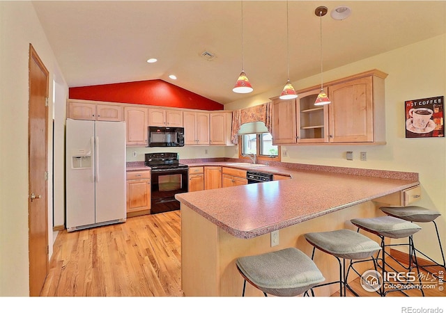 1357 43rd Ave Unit 60, Greeley, CO 80634 - kitchen featuring black appliances, a peninsula, lofted ceiling, light wood finished floors, and a breakfast bar area